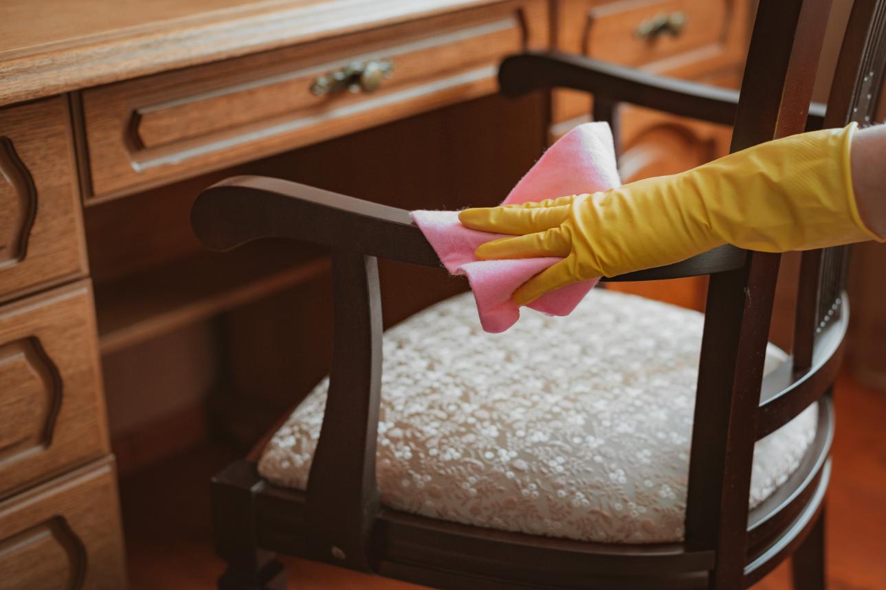 femme professionnelle qui nettoie une chaise rembourrée avec des finition en bois. Nettoyage de meubles a domicile avec Oceanick Nettoyage au Quebec