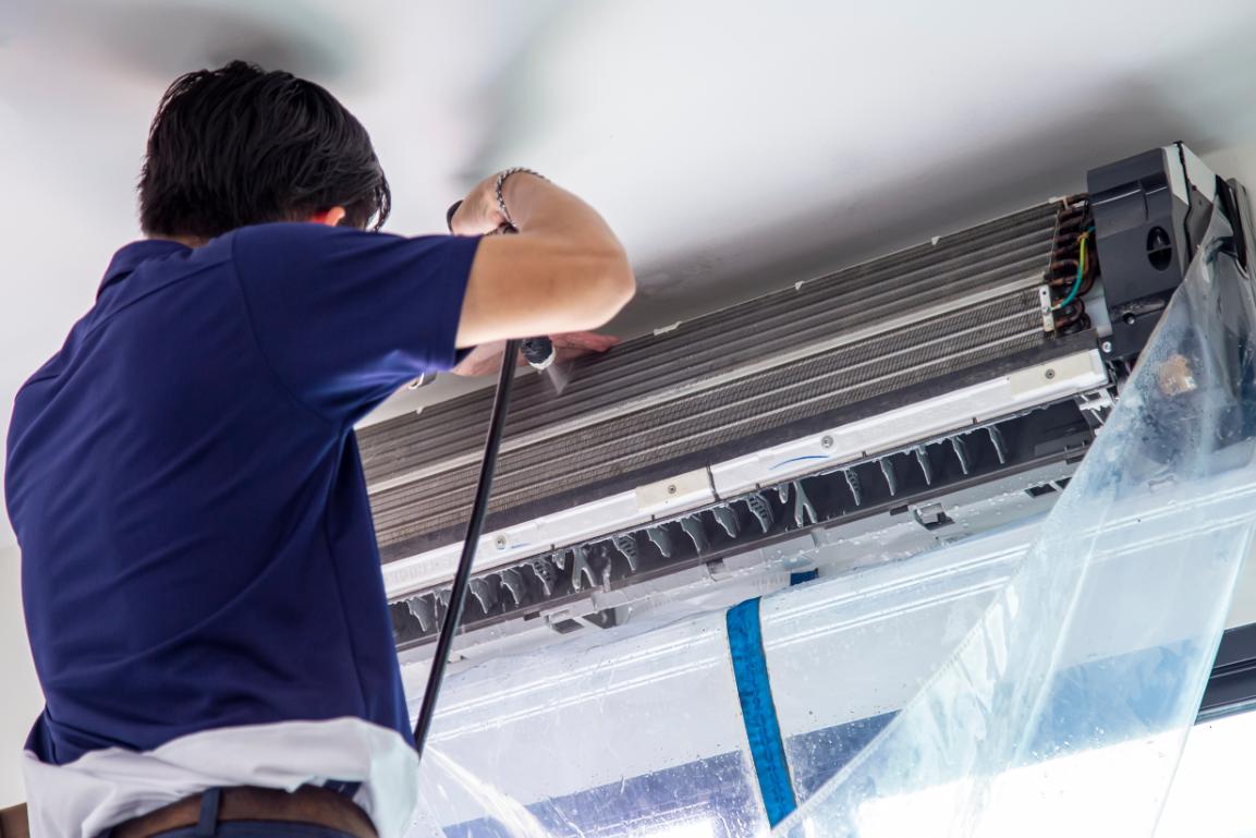 homme professionnel t shirt bleu en train de nettoyer les conduits de ventilation