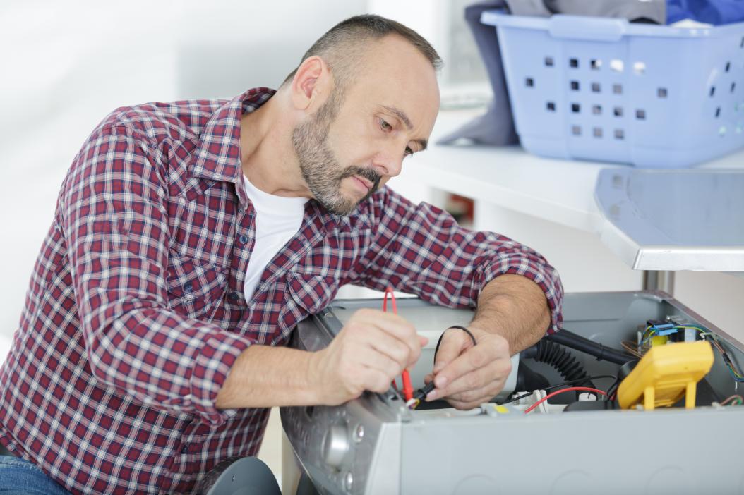 homme professionnel technicien en train d'installer une sécheuse dans un logement. Océanick Nettoyage, spécialistes en nettoyage au Québec.