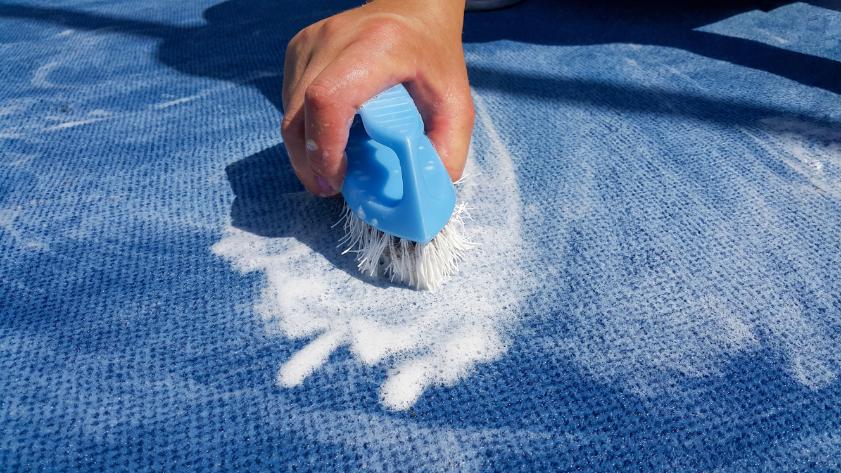 professionnel nettoyage qui frotte un tapis bleu avec une brosse bleu accompagne produit specialise carpette oceanick nettoyage specialiste en nettoyage professionnel a quebec