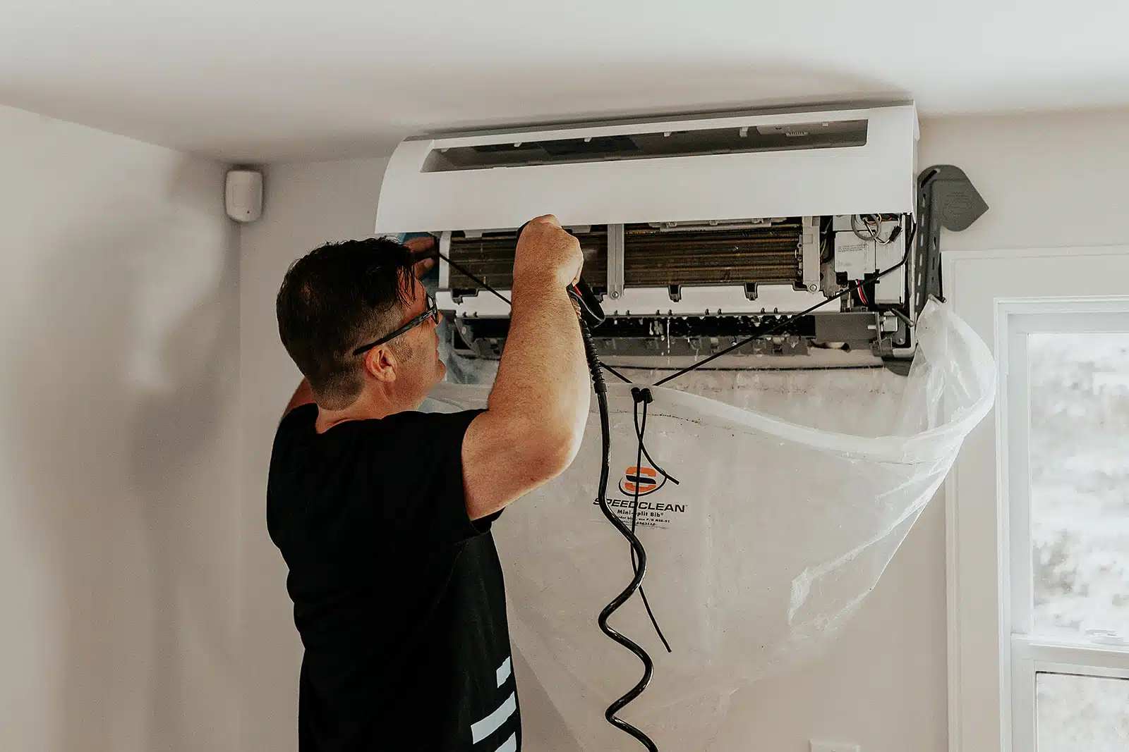 Technicien HVAC nettoyant un climatiseur mural