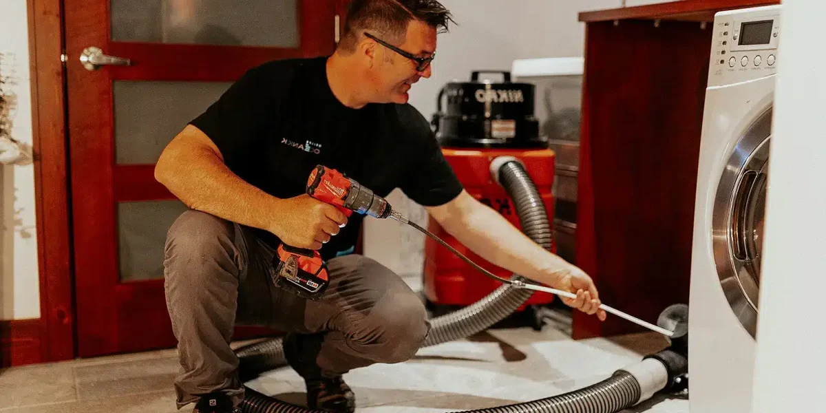 Technicien Océanick Nettoyage nettoyant le conduit de sécheuse avec brosse rotative et aspirateur